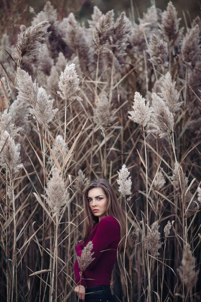 Porträtt av fundersam ledsen ensam kaukasiska blond ung vacker kvinna flicka med långa hår bär jeans, röd skjorta, i skogen fältet bland stora höga växter gräs inne i kameran — Stockfoto
