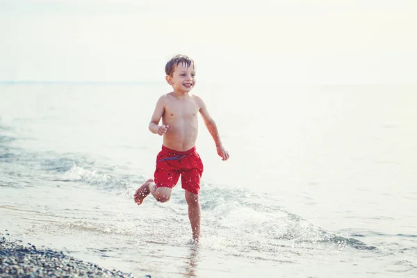boy in red swim shorts running