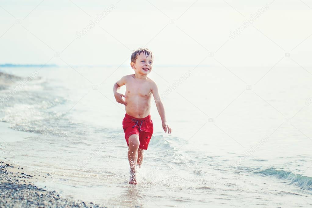 boy in red swim shorts running 