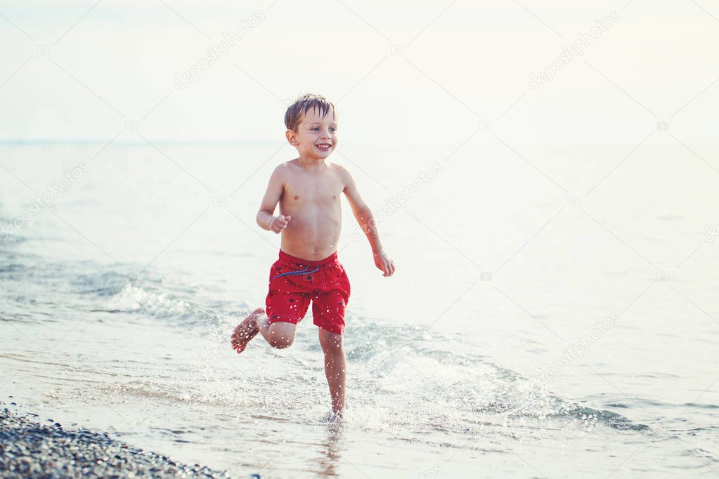 boy in red swim shorts running 