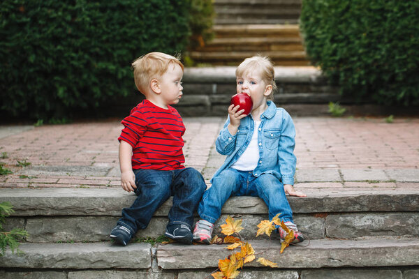 toddlers sitting together sharing  apple