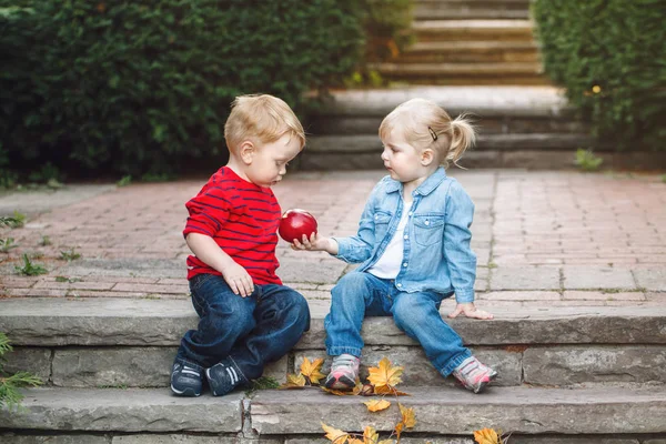 Kleinkinder sitzen zusammen und teilen sich Apfel — Stockfoto