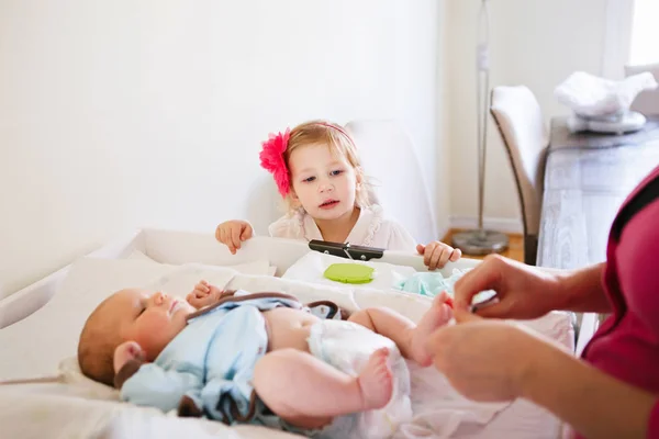 Matka a dcera měnit plenky baby — Stock fotografie