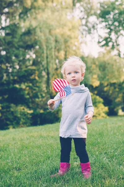 Niña sosteniendo y ondeando bandera americana —  Fotos de Stock