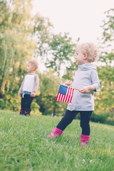 девочка и мальчик улыбаются и машут американскими и канадскими флагами
