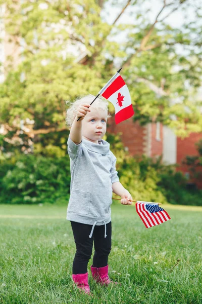 Gadis memegang melambaikan bendera Amerika dan Kanada — Stok Foto