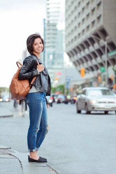 girl  holding backpack  in city street