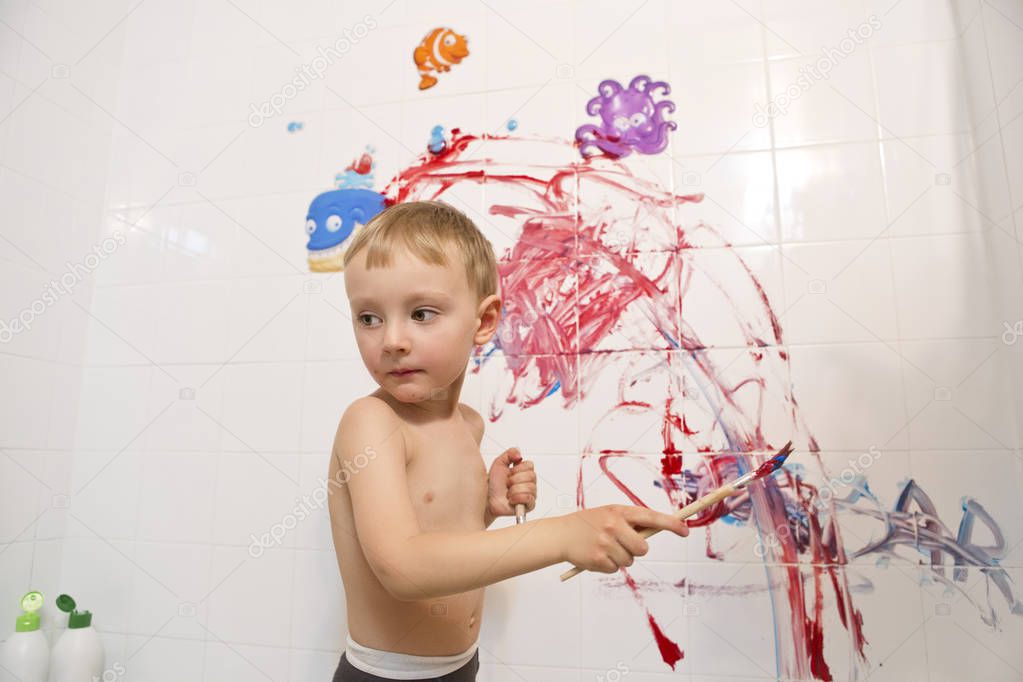 little boy painting wall in bathroom