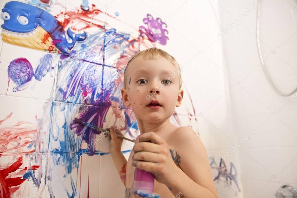 little boy painting wall in bathroom