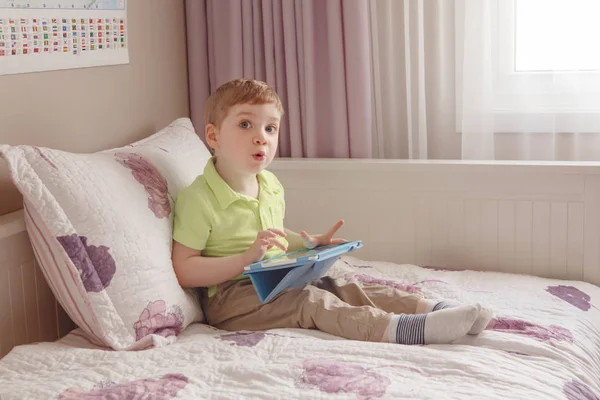 Anak balita duduk di tempat tidur bermain dengan meja digital — Stok Foto