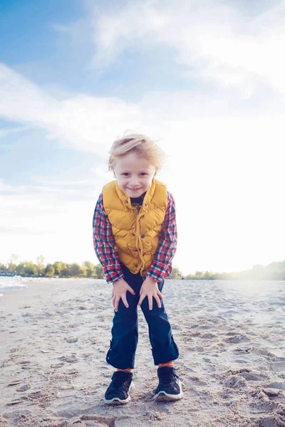 Blond kille står på sand beach — Stockfoto