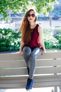 Kız parkta bankta oturuyor.   