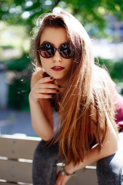 Kız parkta bankta oturuyor.    