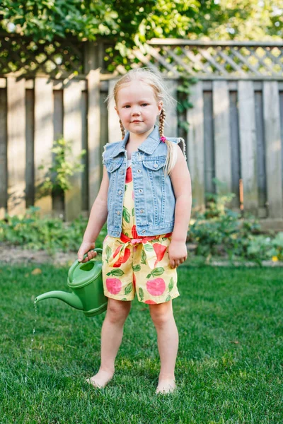 Porträtt av lilla flicka vattning gröna växter — Stockfoto