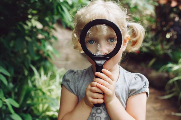 Bambina guardando attraverso lente d'ingrandimento — Foto Stock