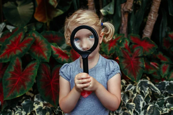 Little girl looking through magnifying glass — Stock Photo, Image
