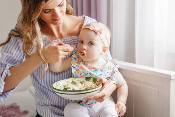 Mère nourrissant sa petite fille avec des légumes — Photo