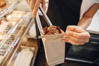 Muffin pasta kahverengi torbaya koyarak beyaz beyaz garson barista bir kadın portre makro çekim. İş yerinde, küçük iş kavramı kişi