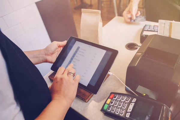 Closeup shot of caucasian cashier hands. Seller using touch pad for accepting client customer payment. Small business of coffee shop cafeteria.