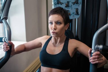 Güzel orta yaşlı beyaz beyaz esmer kadın kısa saçlı ve mavi gözlü spor salonunda egzersizleri yapıyor portresi