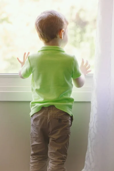 家の外の窓からみる白人の白人子少年の肖像画 バックからの眺め 誰かを待っている子供 — ストック写真
