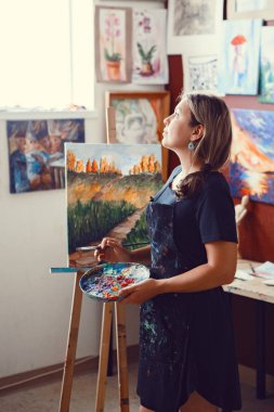 Genç güzel orta yaş beyaz beyaz kadın sanatçı sanat Studio akrilik boya ile resim çizim tuvali üzerinde portresi. Arkadan görüntüleyin. Yaşam tarzı etkinlik hobi kavramı