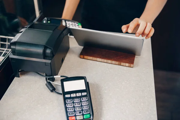 Closeup shot of caucasian cashier hands. Seller using touch pad for accepting client customer payment. Small business of coffee shop cafeteria.