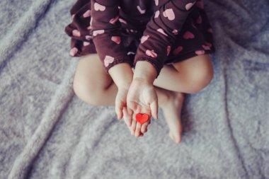 Closeup makro yetişkin üst çocuğun palms bir grup küçük kırmızı ve mor kağıt köpük kalplerin tutan eller. Yaşam tarzı ve mutlu çocukluk kavramı. Sevgililer günü kutlama. 