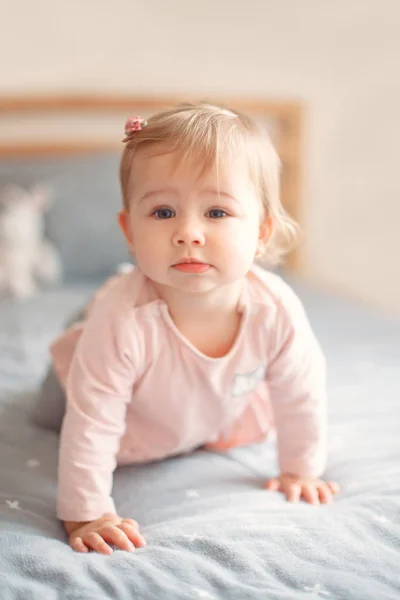 愛らしい白人金髪笑みを浮かべて赤ちゃんとかわいい女の子の寝室のベッドの上に座っているピンクのシャツに青い目の肖像画 自然な感情の表情 幸せな子供時代のライフ スタイル コンセプト — ストック写真