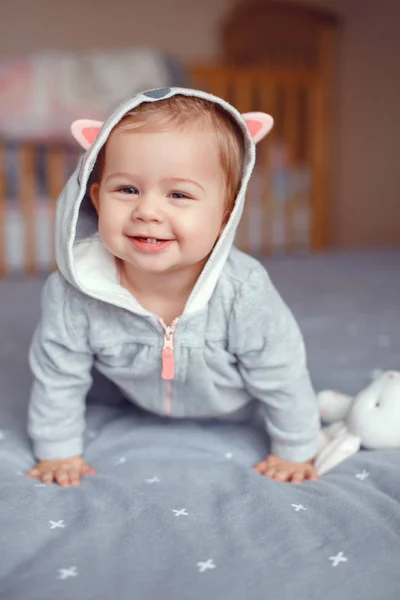 かわいい白人金髪笑みを浮かべて赤ちゃんの愛らしい少女灰色パジャマの寝室で狐猫動物フード付きの肖像画 自然な感情の表情 幸せな子供時代のライフ スタイル コンセプト — ストック写真