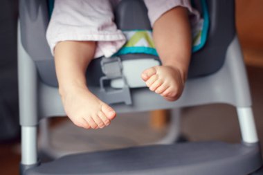 Tombul bebek bacaklar ayak closeup. Küçük çocuk yüksek sandalyede oturuyor. Şirin çocuk makro detay