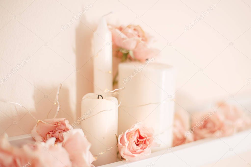 Decoration of  room for birthday celebration. Macro closeup of soft tender light pink roses and white candles on shelf for party