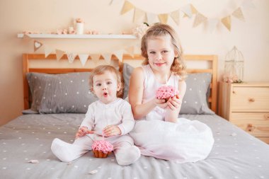 Doğum günü kutlama iki sevimli sevimli beyaz beyaz girsl holding pembe kek. Çocuklar eğleniyor yatak yatakta birlikte oturan gülümsüyor. Kapalı kek smash ilk yıl kavramı Anasayfa