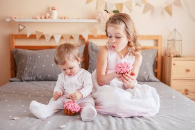 Doğum günü kutlama iki sevimli sevimli beyaz beyaz girsl holding pembe kek. Çocuklar eğleniyor yatak yatakta birlikte oturan gülümsüyor. Kapalı kek smash ilk yıl kavramı Anasayfa