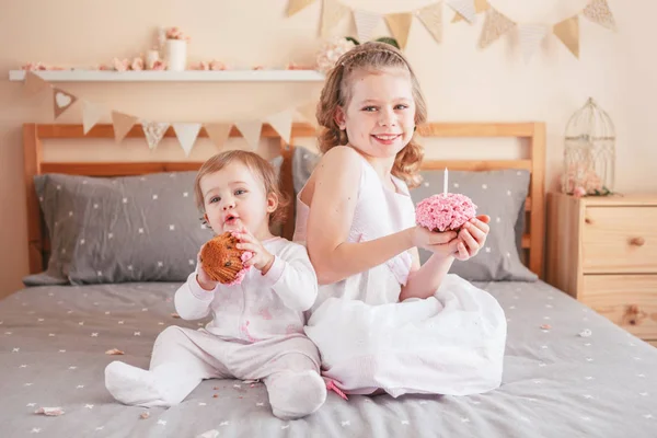 两个可爱可爱的白种白人 Girsl 拿着粉红色的蛋糕庆祝生日 微笑的孩子们坐在一起睡在卧室里玩得开心 首页室内蛋糕粉碎第一年概念 — 图库照片
