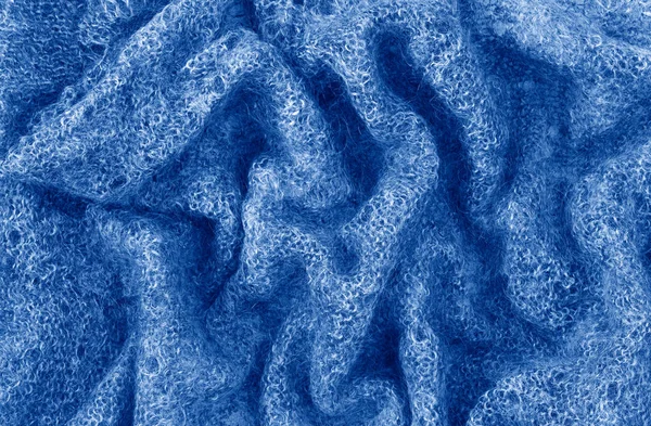 Detailní makro textura pleteného tmavomodrého vlněného šátku. Strukturované oděvní pozadí s vráskami a záhyby. Toned with trendy 2020 year color blue. — Stock fotografie