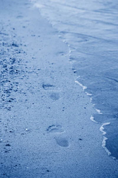 Closeup of feet traces footprints on sand  beach by sea ocean wa — Stock Photo, Image