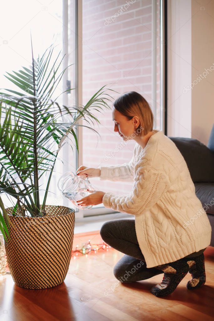 Happy Caucasian woman pouring water from glass jar on green home