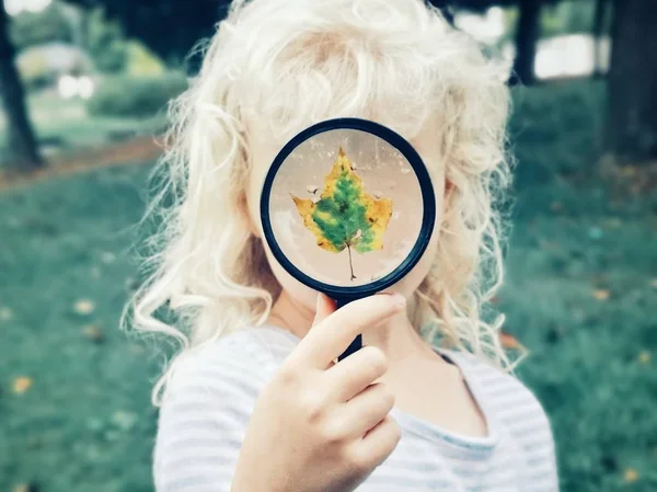 Klein kind meisje met vergrootglas en het bedekken van haar gezicht — Stockfoto