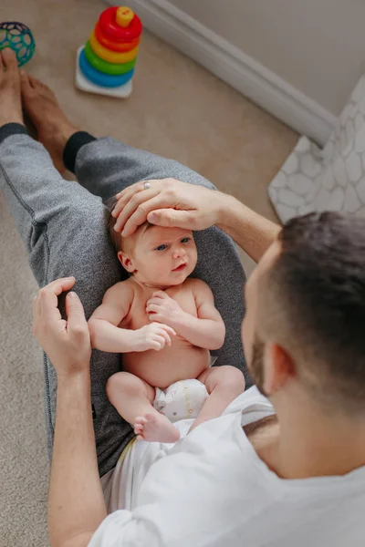 Feliz padre caucásico sosteniendo al bebé recién nacido de rodillas. Hombre p — Foto de Stock