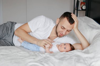 Mutlu Kafkasyalı baba yeni doğmuş bebekle evdeki yatak odasında yatıyor.