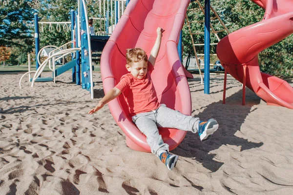 Activa feliz divertido sonriente caucásico chico niño deslizándose en playgr — Foto de Stock