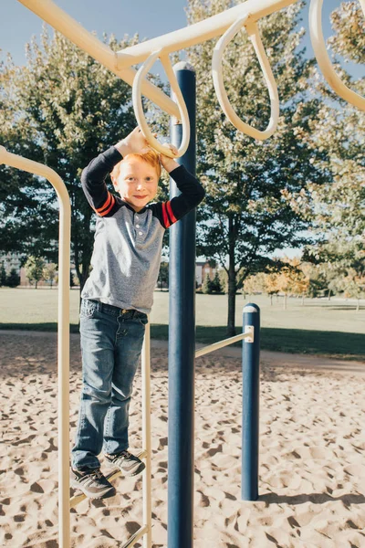 Jonge blanke jongen opknoping op aap bars in park op de speelplaats — Stockfoto