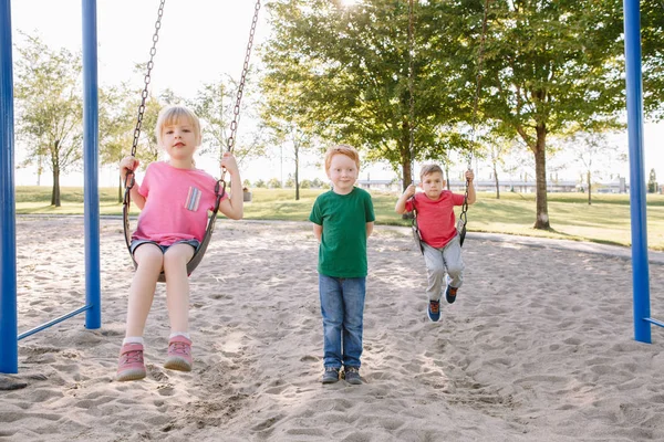 Gelukkig glimlachen kleine kleuter meisje en jongens vrienden swingen op — Stockfoto