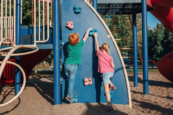 Kleine kleuter jongen en meisje klimmen rots muur op speelplaats o — Stockfoto