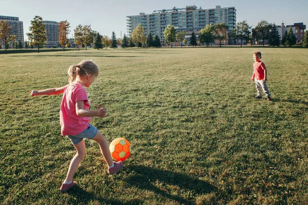 Μικρό κορίτσι προσχολικής ηλικίας και αγόρια φίλους που παίζουν ποδόσφαιρο στο — Φωτογραφία Αρχείου