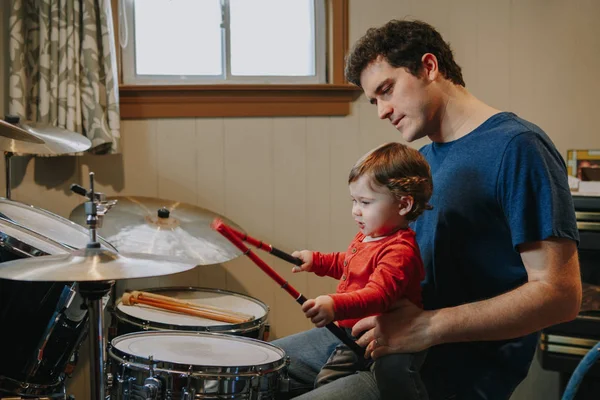 Far lärde pojken att spela trummor. Förälder med småbarn som har roligt och umgås. Pappa och grabben spelar musik. Familjehobby och fritid. — Stockfoto