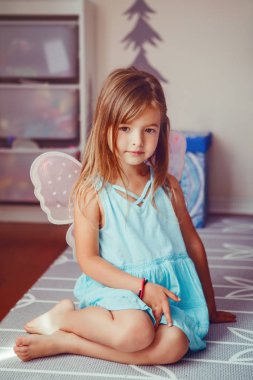 Evde peri prensesi rolünü oynayan sevimli, sevimli, güzel giyimli anaokulu kızı. Çocuk yaratıcılığı hayal gücü ve fantezi rüya kavramı. Mavi elbiseli güzel beyaz çocuk peri ya da elf taklidi yapıyor.. 