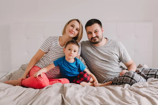Familia Tres Personas Sentadas Cama Dormitorio Mirando Cámara Madre Padre —  Fotos de Stock
