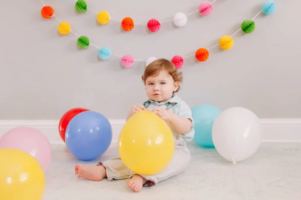 有趣的白人男婴庆祝他的第一个生日 小孩蹒跚学步 带着彩色气球坐在地板上 庆祝家里的活动或聚会 生日快乐生活方式的概念 — 图库照片